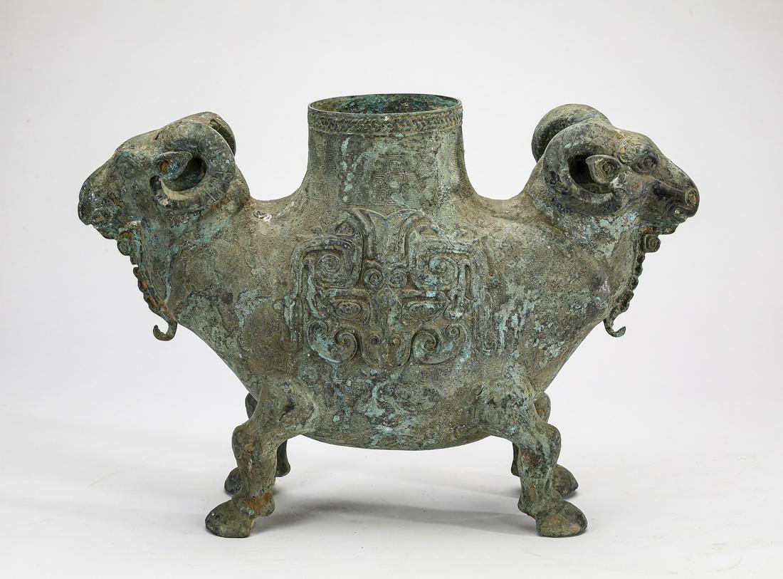 Shang style Chinese bronze double ram 'zun', 13"h: Shang style Chinese bronze double ram 'zun' or wine vessel, executed in the shape of two addorsed rams, the heads set in opposite directions and having scrolled horns, sharing the same hollow body dec