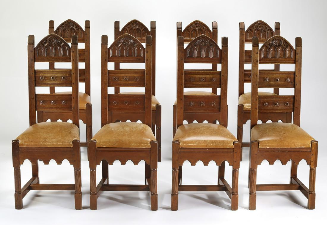 (8) Continental Gothic Revival side chairs in leather: Set of eight Continental Gothic Revival oak and leather upholstered side chairs, late 19th century, each having a tall ladder back composed of a Gothic arch-shaped top rail carved with tracery, a stra