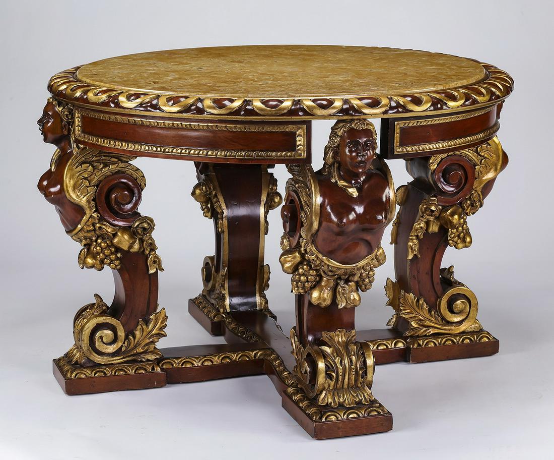 Carved and parcel gilt mahogany marble top table: Mahogany and marble center table in the Baroque taste, having a tan breccia marble top inset in a gadrooned frame, rising on four winged term figures draped with fruited garlands above acanthus scroll