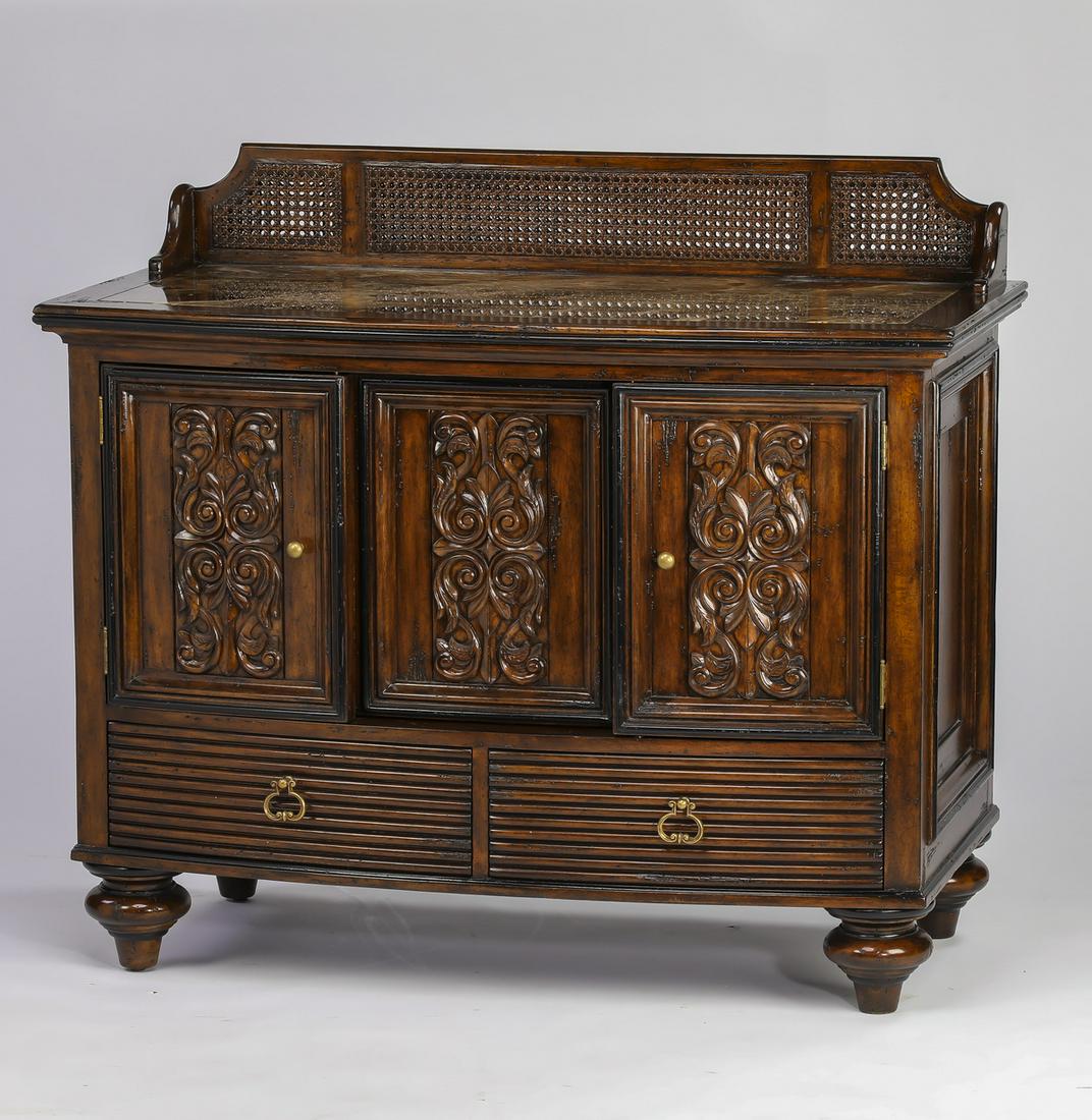 Marge Carson marble top bowfront commode: Marge Carson commode in the Neoclassical taste, having a bowfront case with inset marble top and caned backsplash, fitted with two carved doors flanking a sliding panel, opening to an adjustable shelf