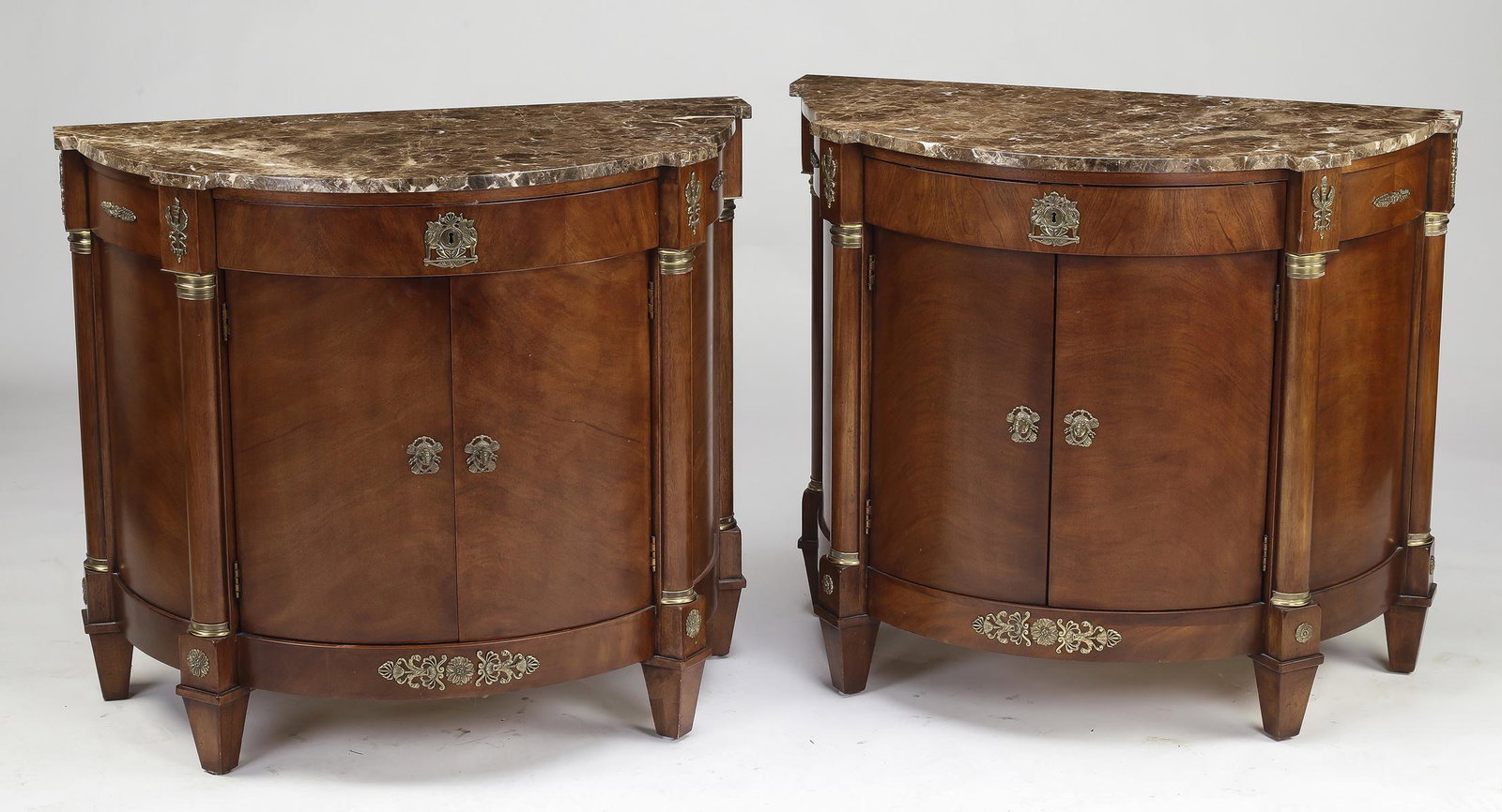 (2) Henredon marble top commodes: Pair of Henredon marble top demilune commodes, each having a demilune marble surface resting on a conforming commode with a long drawer with silver storage cloths over two doors opening to two shelves