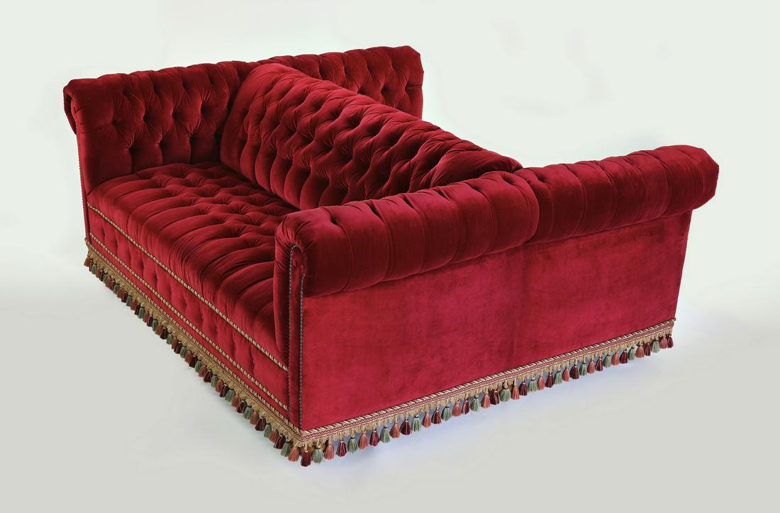 Edwardian style dual sided tufted red velvet sofa: Dual sided button tufted red velvet sofa in the Edwardian taste, late 20th century, of square form with rolled arms, trimmed with spiraling gold cord and burgundy, blue, and rose tassels, 30"h x 75"l 
