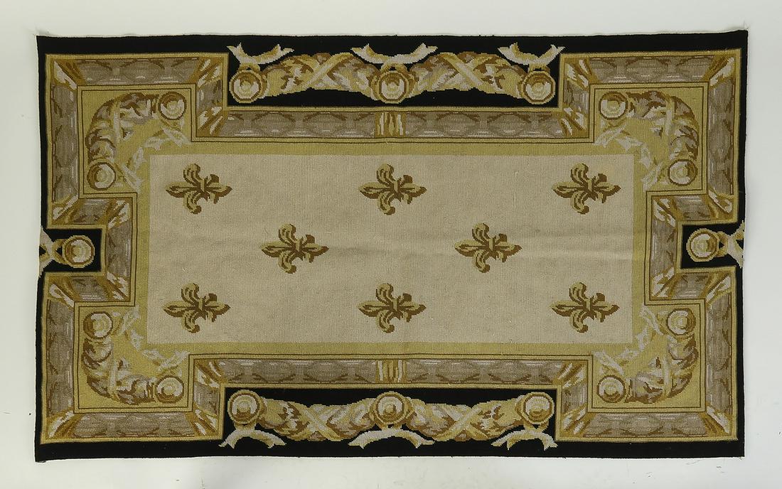 Aubusson style needlepoint rug with fleur de lis: Aubusson style needlepoint rug in the Louis XVI style, having a cream field ornamented with gold toned fleur de lis, framed in a garland border edged in black, 56.5'l x 35"w.