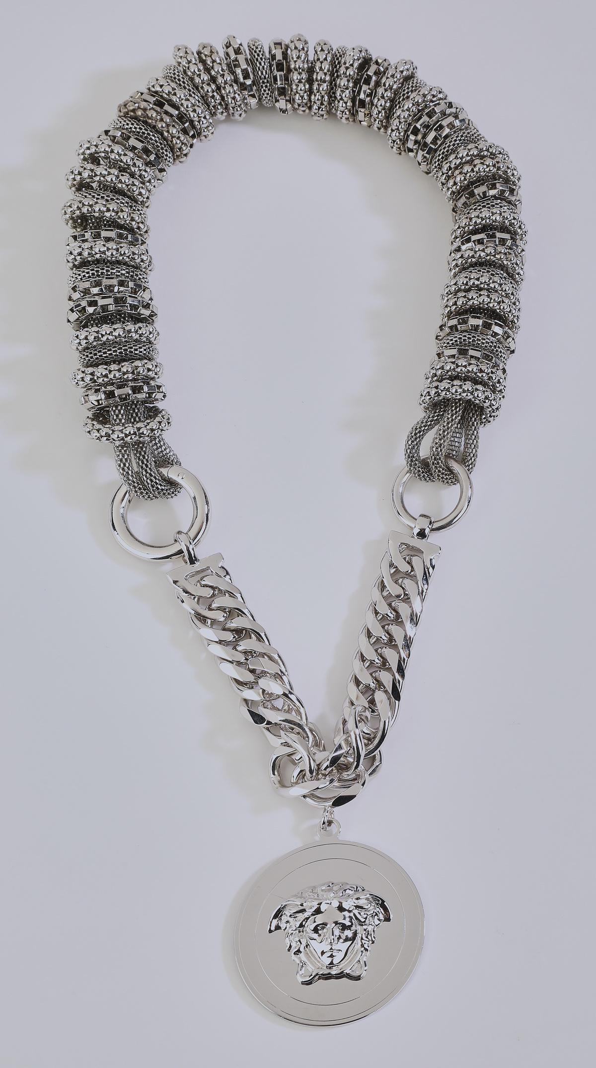 Vintage Versace necklace w/ logo pendant, 18"l: Vintage Versace necklace, executed in woven silver tone chain threaded through textured rings and connected to a curb link chain suspending a large Versace logo medallion, featuring the head of Medusa