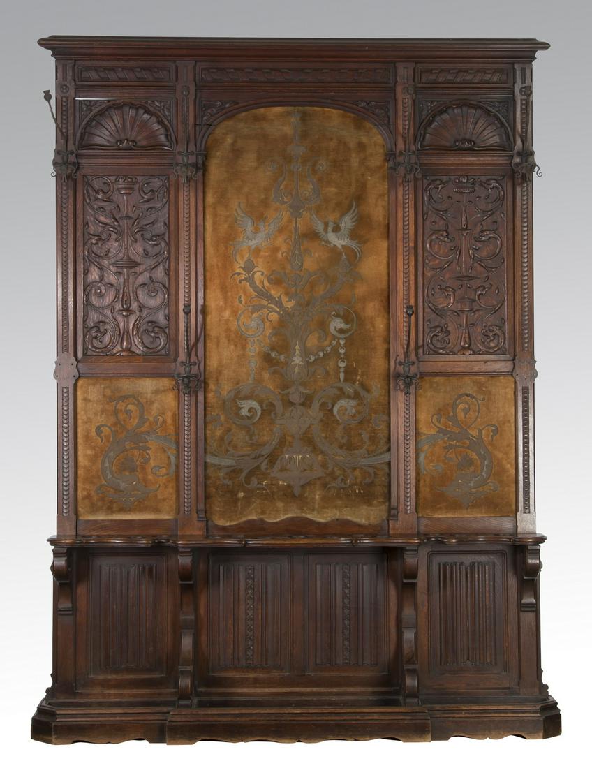 French carved oak hall tree w/ embroidered panel: Oversized French Renaissance Revival carved oak hall tree, circa 1880, having a molded cornice above three panels, the center with a gilt embroidered velvet inset panel depicting urns, scrolling vines