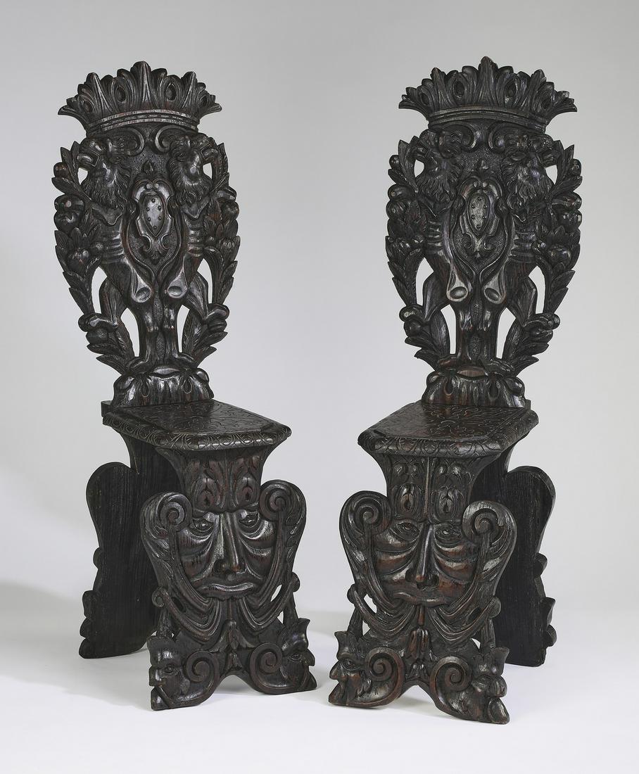 (2) 19th c. Italian carved oak hall chairs: Pair of Italian carved oak sgabello hall chairs, mid to late 19th century, each of typical form, having a crown crest, pierced foliate back, and a rectangular seat, rising on shaped panel supports dep
