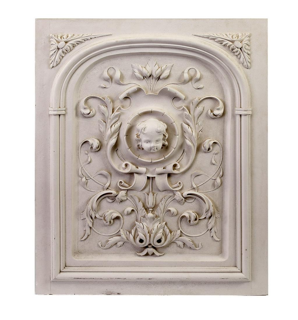Cast plaster figural putto architectural panel, 29"h: Figural architectural panel, depicting the face of a putto centered by acanthus leaf scrollwork and framed by a molded arch, crafted of cast plaster, 29"h x 23.75"w x 1.5"d.