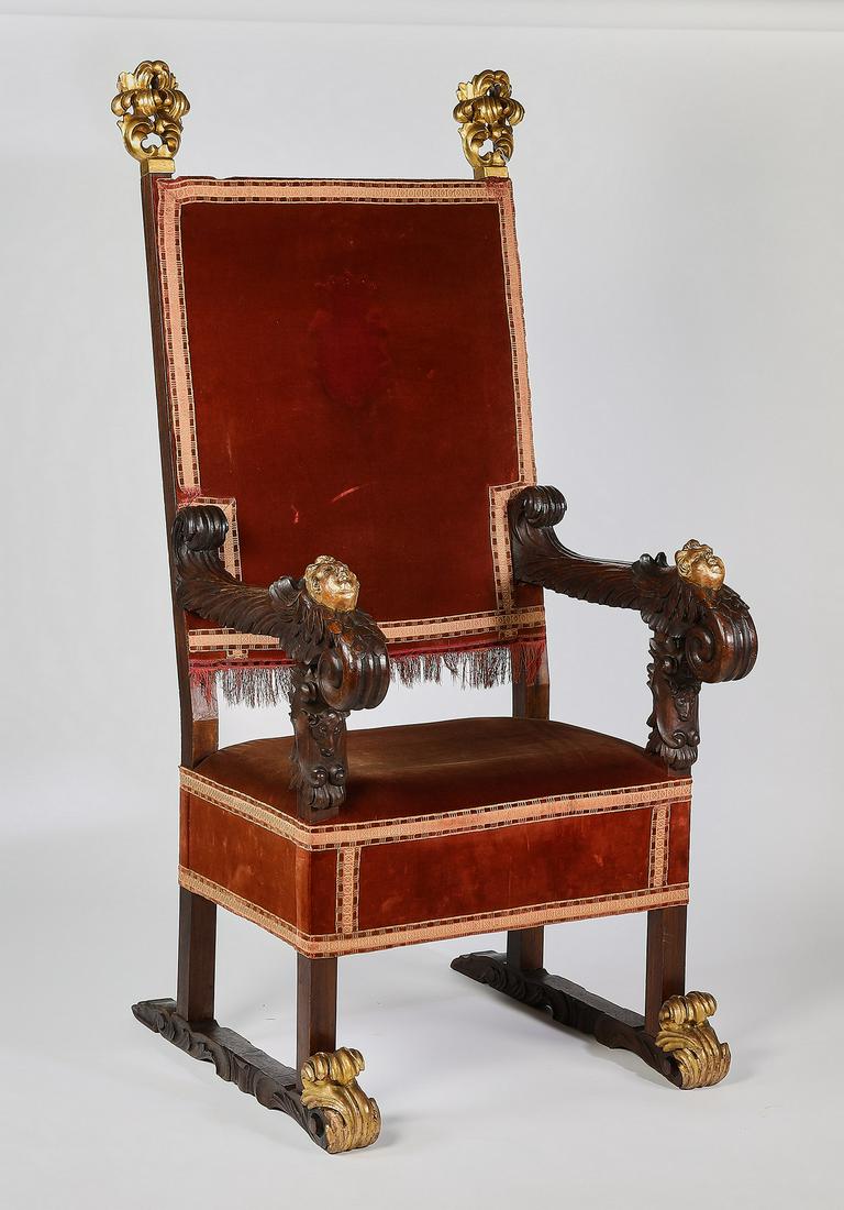 19th c. Continental carved oak throne chair: Continental red velvet and parcel gilt carved oak throne chair in the Renaissance taste, 19th century, having finger carved gilt finials over a square back and seat, and foliate carved arms with cheru