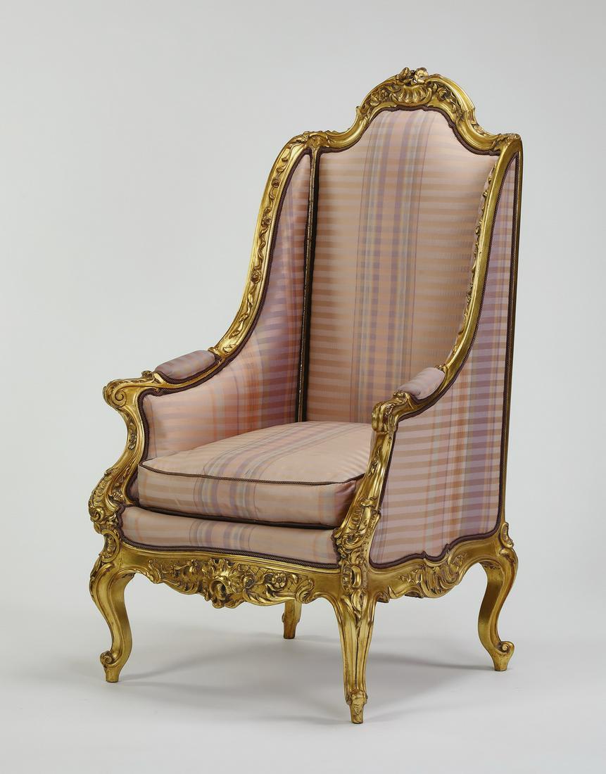 Louis XV style giltwood and silk bergere, 50"h: Louis XV style giltwood bergere, upholstered in pale pink plaid silk, having a rocaille carved arched crest flowing into partially upholstered arms, flanking a drop-in cushion seat above a rocaille ca