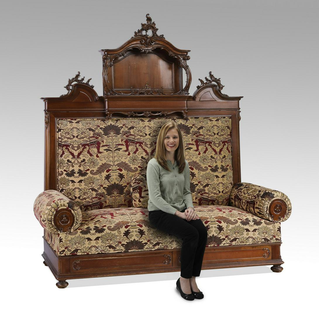 Monumental custom upholstered carved walnut settee: Custom upholstered carved walnut settee, having a rocaille cartouche rising on an arched pediment above acanthus scrollwork, centering an open niche, flanked on either side by rocaille cartouches rest