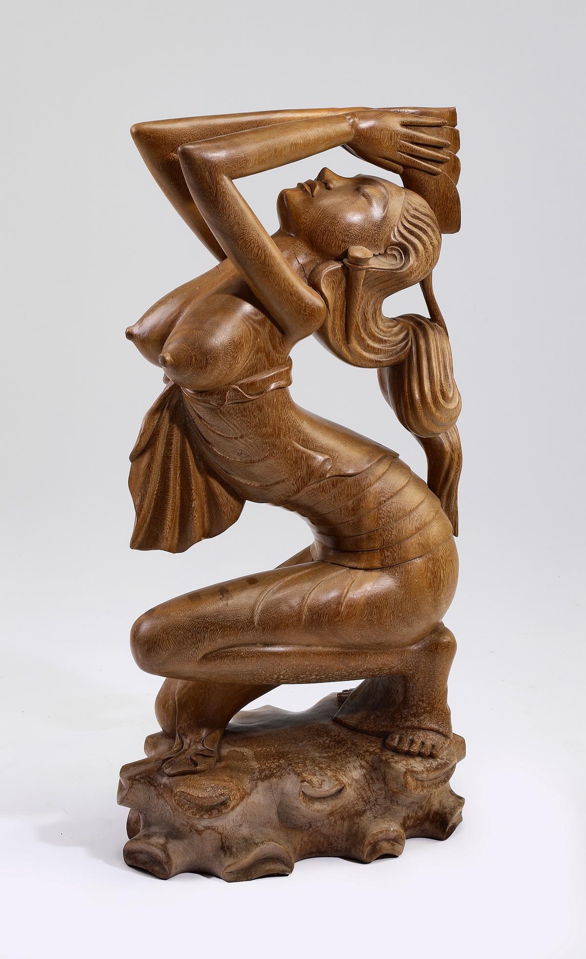 Large Balinese carved teak sculpture, 33"h: Balinese carved teak sculpture, depicting a beauty in a half kneeling pose with her hands over her thrown back head, and a sarong wrapping her lower torso, the whole resting on a rocky outcropping, 33