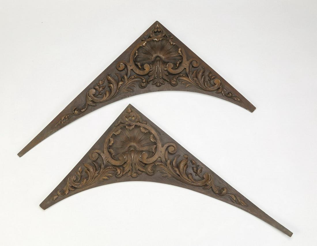 (2) Cast resin architectural elements, 29"l: Pair of cast resin architectural elements, of triangular form centering a foliate fan framed by 'C' scrolls and acanthus swags, stained a deep sable, 29"h x 18.5"w x .75"d.