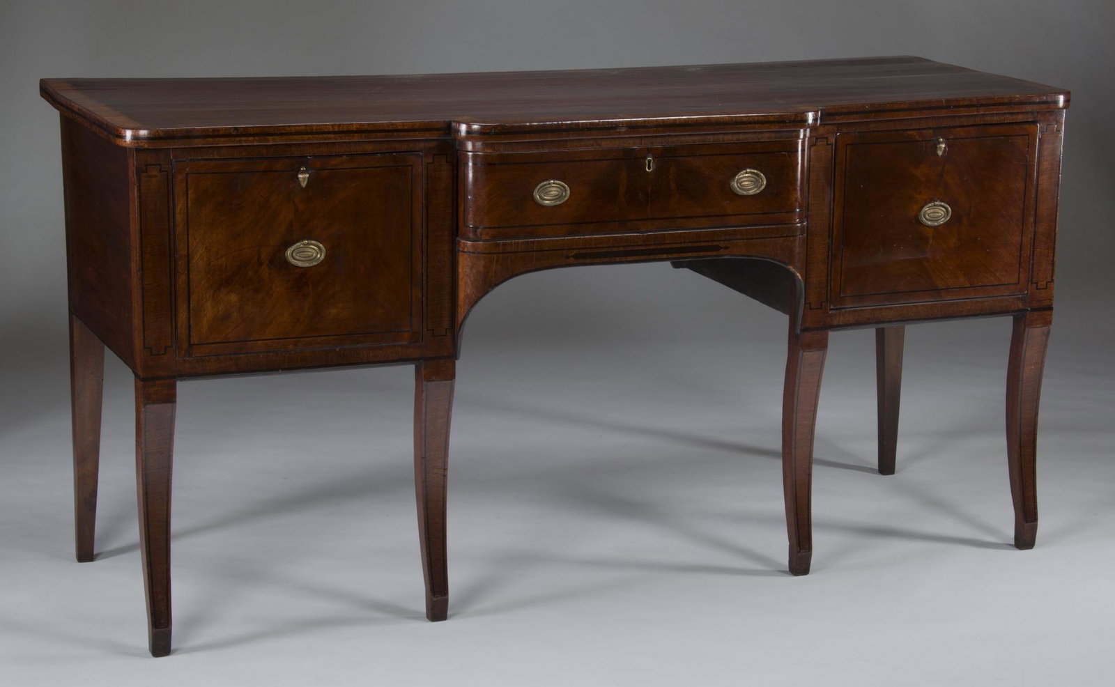 19th c. English mahogany sideboard, 72"w: 19th century George III style mahogany sideboard, the shaped top with banding surmounting the breakout front with a central drawer flanked by a deep drawer and a door cabinet, all opening to custom-fa
