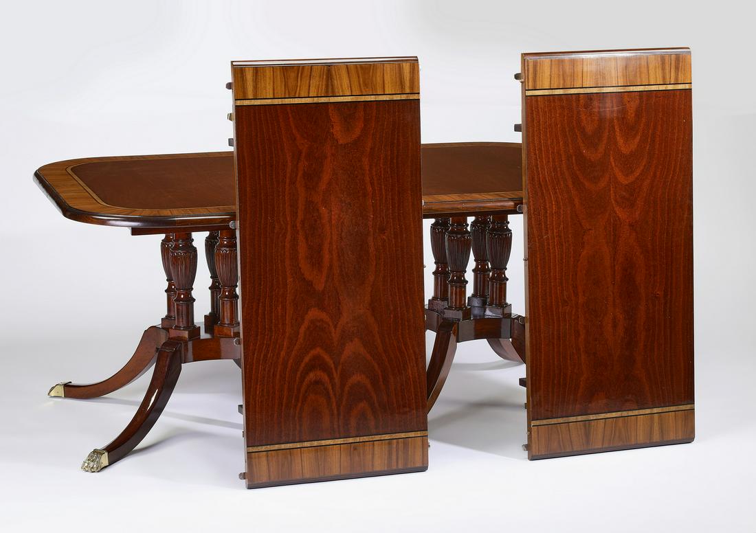 Sheraton style mahogany table w/ two leaves: Sheraton style double pedestal dining table, having a highly figured inlaid mahogany surface rising on two pedestals comprised of turned and carved standards, each terminating in four legs with bronze