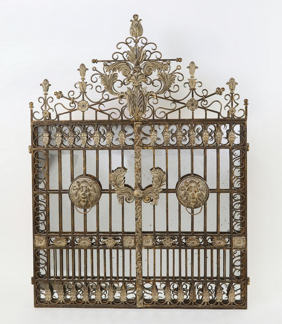 Renaissance style mirror in the form of entry gates: Renaissance style mirror, in the form of a pair of entry gates, having a paint decorated antiqued gold scrolling foliate crest, over a two door gate with lion head pulls and foliate scrolling ornament