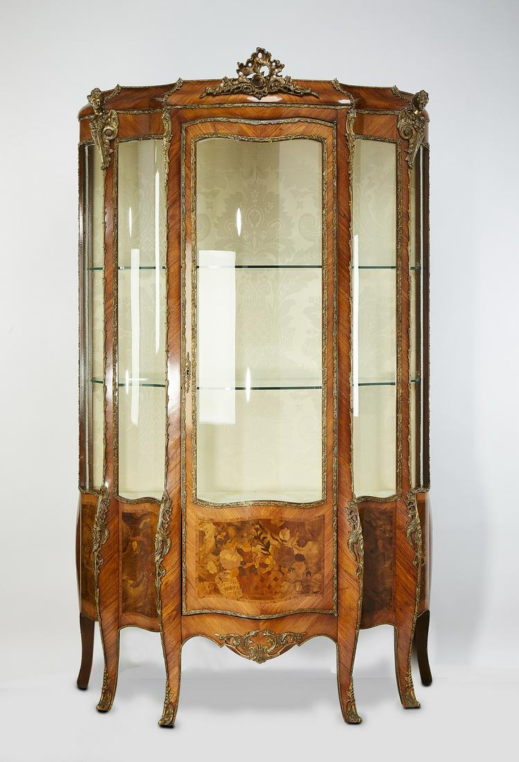 Louis XV style marquetry and bronze mounted vitrine: Italian satinwood, marquetry, and bronze mounted vitrine in the Louis XV taste, of serpentine form, having a cavetto cornice centering a bronze floral mount over a case composed of curving glass panes