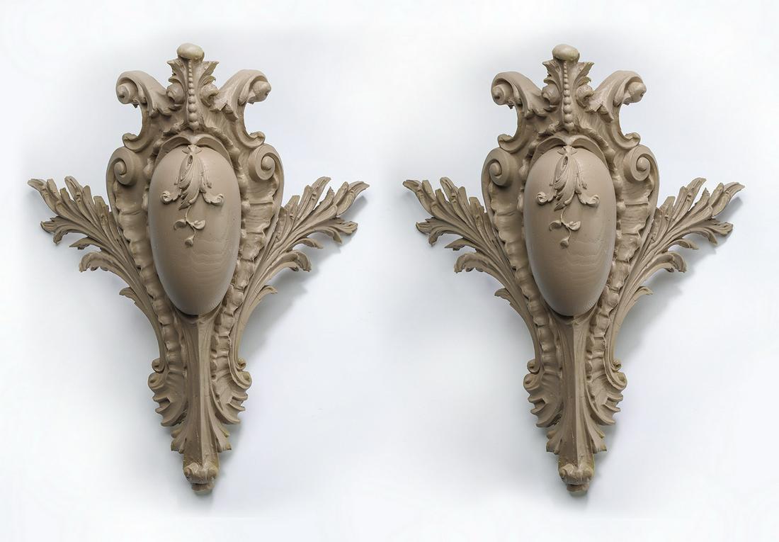 Pair of composite architectural cornerpieces, 21"h: Pair of architectural cornerpieces, each having elaborate acanthus scrollwork centering a carbachon accented with a leafy garland, each crafted of cast composite material, 21"h x 19"w x 12.25"d.