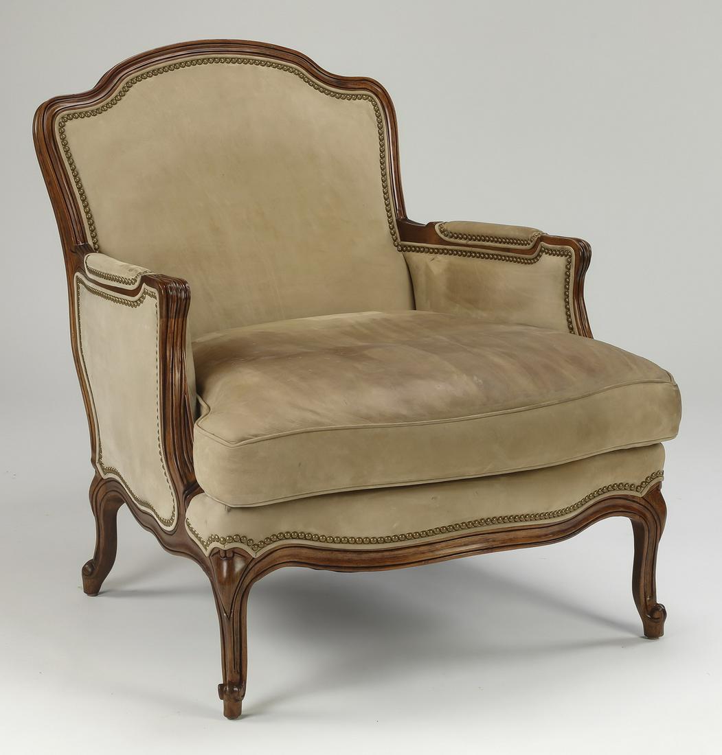 Hancock & Moore mahogany & suede bergere: Hancock and Moore mahogany and suede bergere, having an arched crest surmounting an upholstered back, above a seat with a drop-in cushion and half over rail upholstery with nail head trim, flanked by 