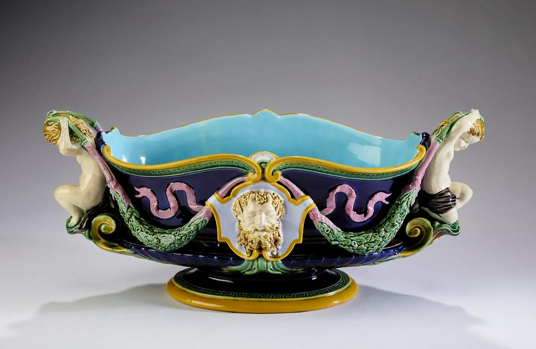 Neoclassical Mintons majolica centerpiece, c. 1874: Mintons majolica centerpiece, in the Neoclassical taste, circa 1874, of navette form, having putti double handles holding swags of laurels leading to masked shields, the whole rising on a pedestal bas