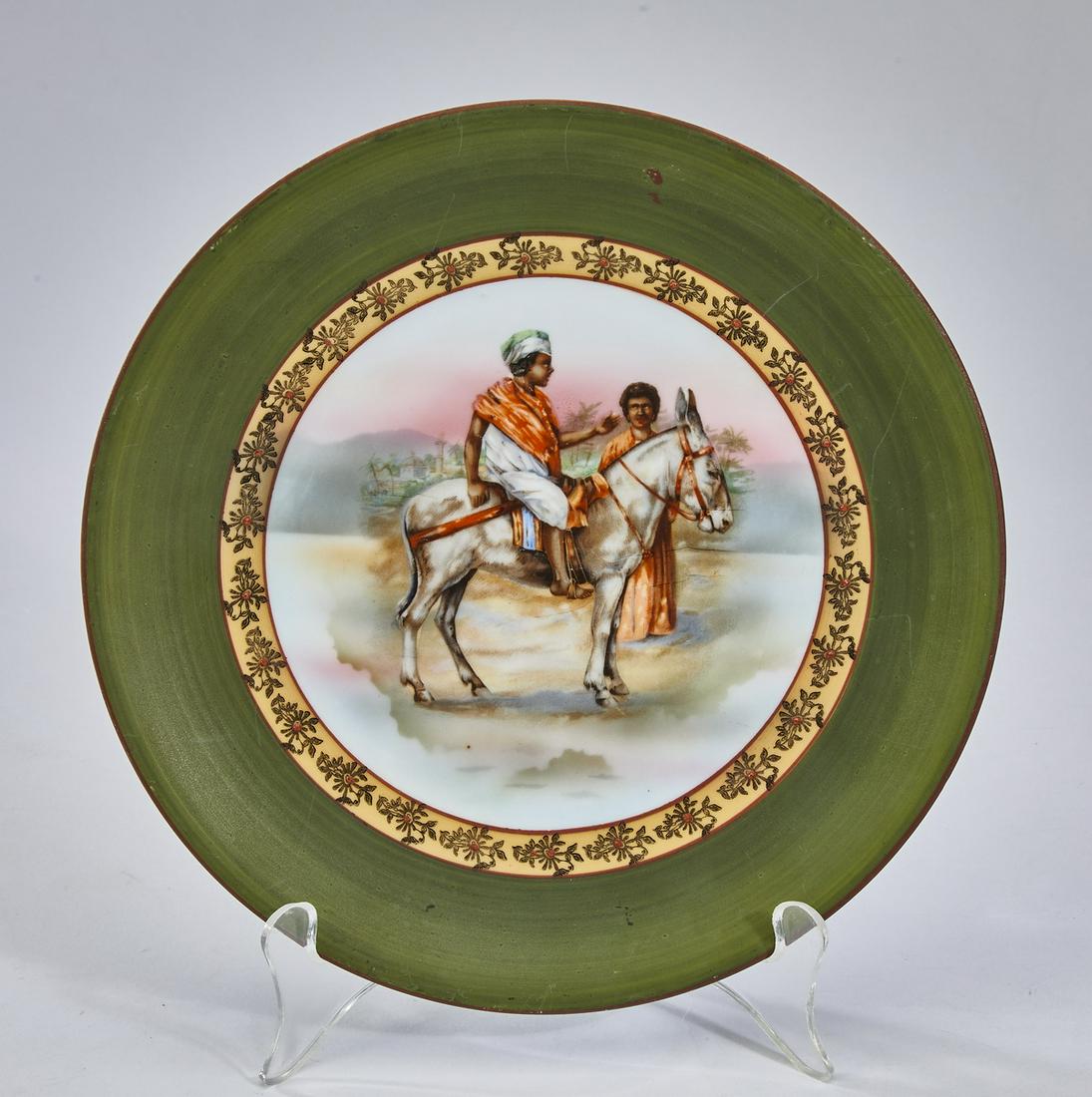 Royal Bayreuth 'Arabian Nights' porcelain plate: Royal Bayreuth 'Arabian Nights' plate, having a forest green rim with a gilt verge, centering a scene of two men in a desert landscape, one on the back of a donkey, maker's mark to underside, 9"dia.