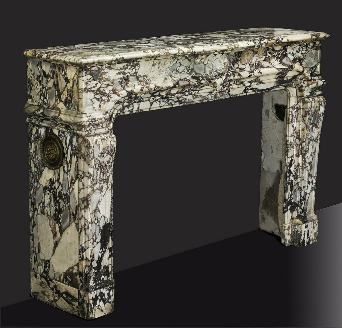 19th c. Italian carved breccia marble mantel: 19th century Italian rouge and cream breccia marble mantel in the Neoclassical taste, having a rectangular top fronted by a demi-lune center, above a frieze centering a Rococo inspired cabochon, risin
