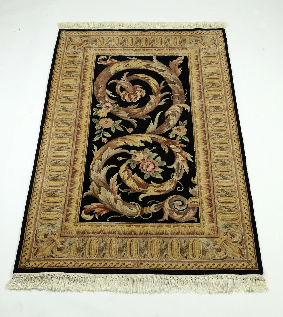 Hand knotted wool Aubusson style pile rug, 6' x 4': Hand knotted wool Aubusson style pile rug, the dark field centering acanthus scrolls with floral embellishments in taupe, tan, pale green, and pink, with a repeating oval border in gold and taupe, 5' 