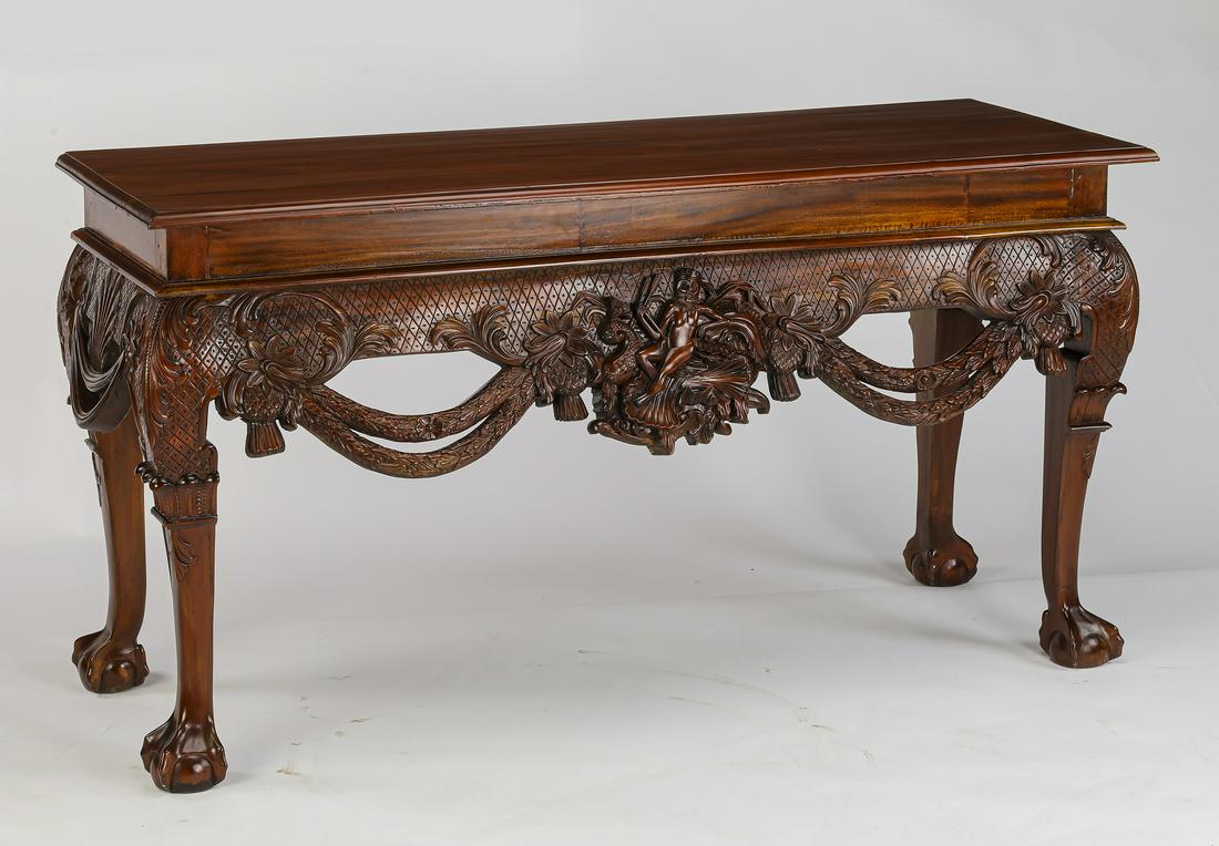Highly carved mahogany console, 59"w: Highly carved mahogany console, having a rectangular floating surface above a highly carved apron with pierced floral swags centering a figural cartouche accented with dolphins, foliates, and fruits, 