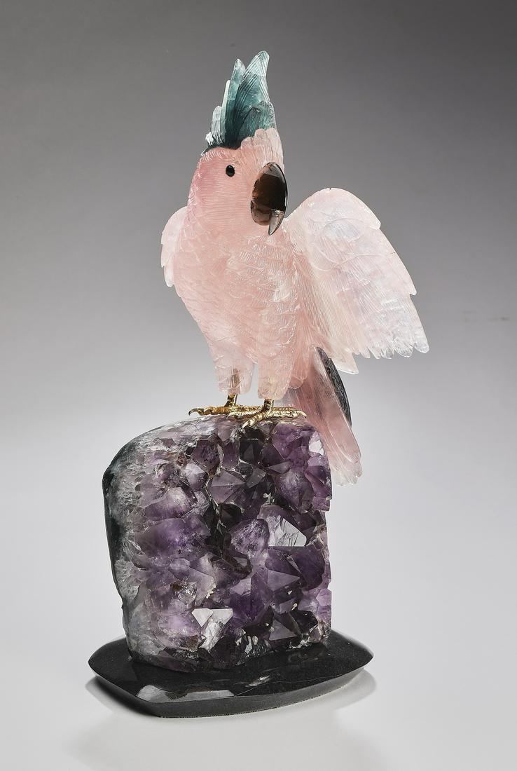 Carved Brazilian mineral specimen cockatoo: Carved mineral specimen cockatoo, executed in rose quartz, smoky quartz, and serpentine, depicted perched on an amethyst specimen, resting on a black dolomite base, marked Amsterdam Sauer, Brazil, 13"