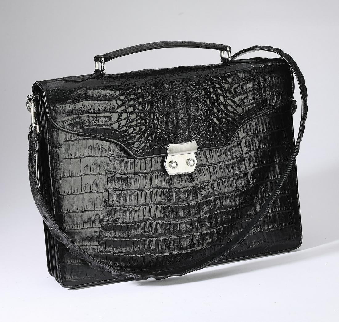 Black crocodile leather shoulder bag: Black crocodile leather shoulder bag, having a hand grip and shoulder strap, opening to card holders and a slip pocket, fitted with two compartments with a pen holder and pockets, 12"h x 15"w x 3"d.
