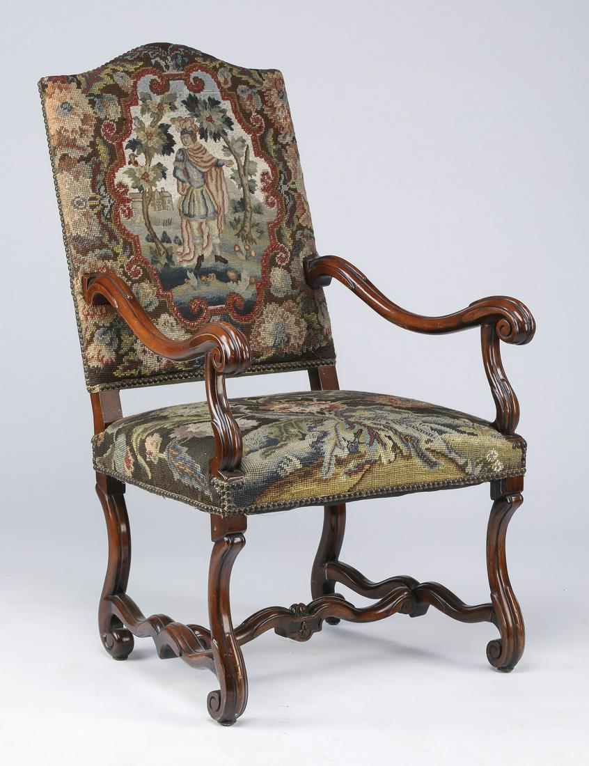 19th c. French carved walnut armchair in needlepoint: 19th century French carved walnut armchair with needlepoint upholstery, the backrest depicting a medieval figure in a pastoral setting, the seat with foliate sprays in a palette of blue, cream, and re