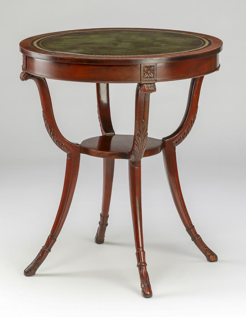 Regency style mahogany and leather gueridon: Regency style mahogany and leather gueridon, having a round top inset with an emerald leather blotter, above a wide apron carved with rosettes, rising on sinuous acanthus carved supports joined by a c