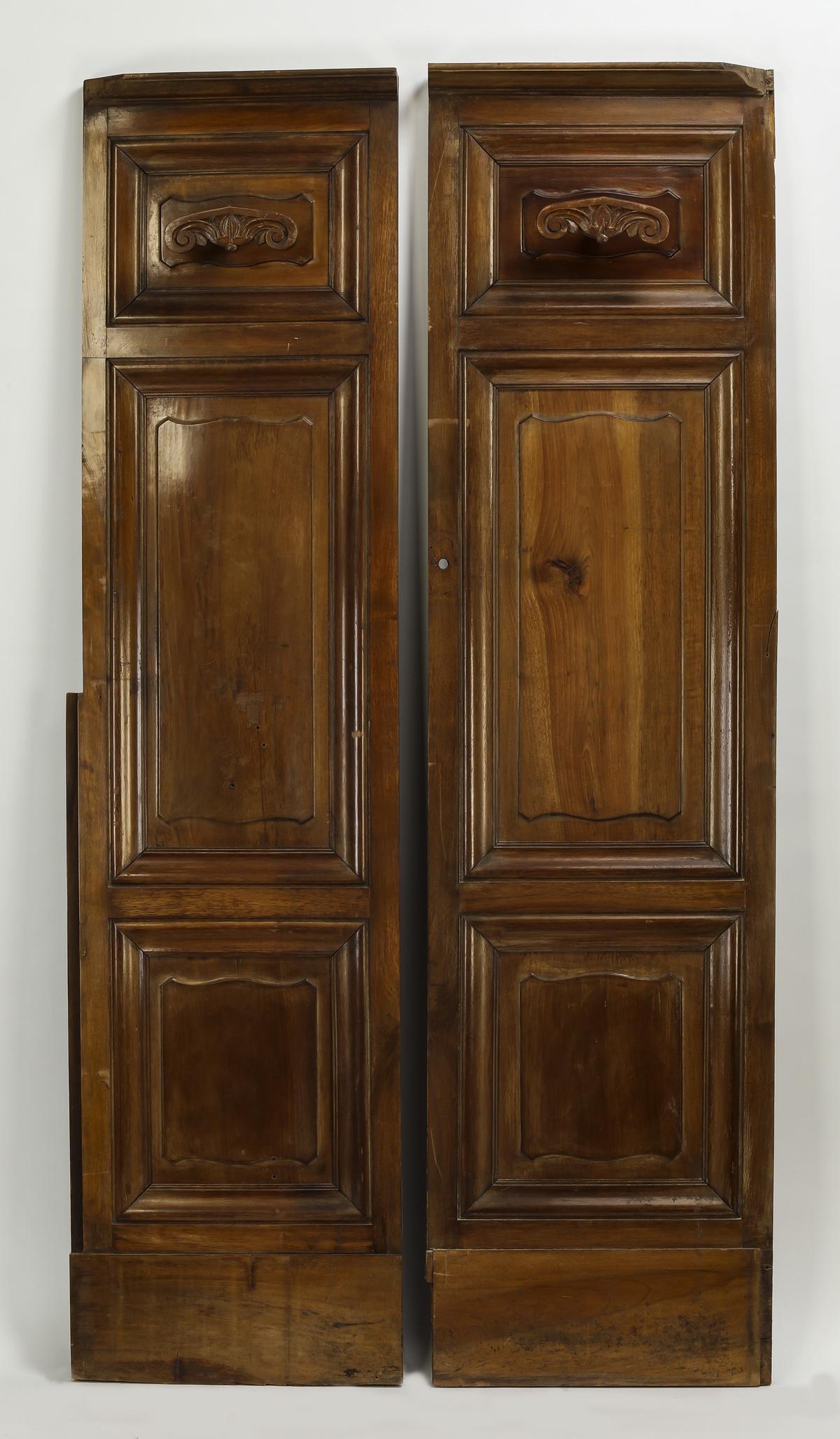 (2) 19th c. French walnut panels w/ coat hooks, 75"h: Pair of 19th century French carved walnut architectural panels, each having a carved wood coat hook above two raised panels, 75"h x 19.75"w x 5"d.