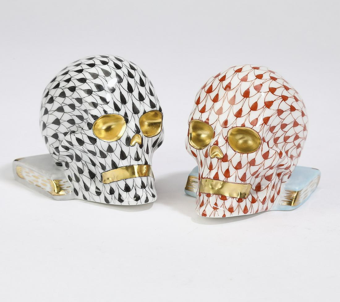 (2) Herend porcelain skulls on books, 2"h: Pair of Herend porcelain skulls on books, each executed in the net pattern with gold accents, comprising one black net and one rust net, maker marked, 2"h x 2"w x 2.5"d.