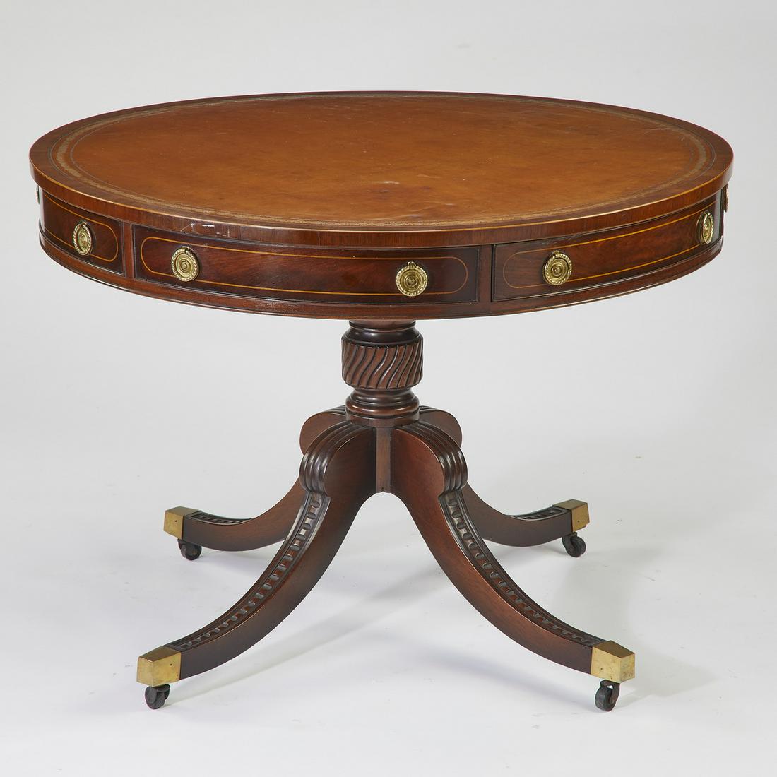 Baker Furniture mahogany and leather center table: Baker Furniture mahogany and leather center table in the Regency taste, having a circular top with an inset leather blotter, above a wide apron with two drawers, surmounting a turned pedestal standard