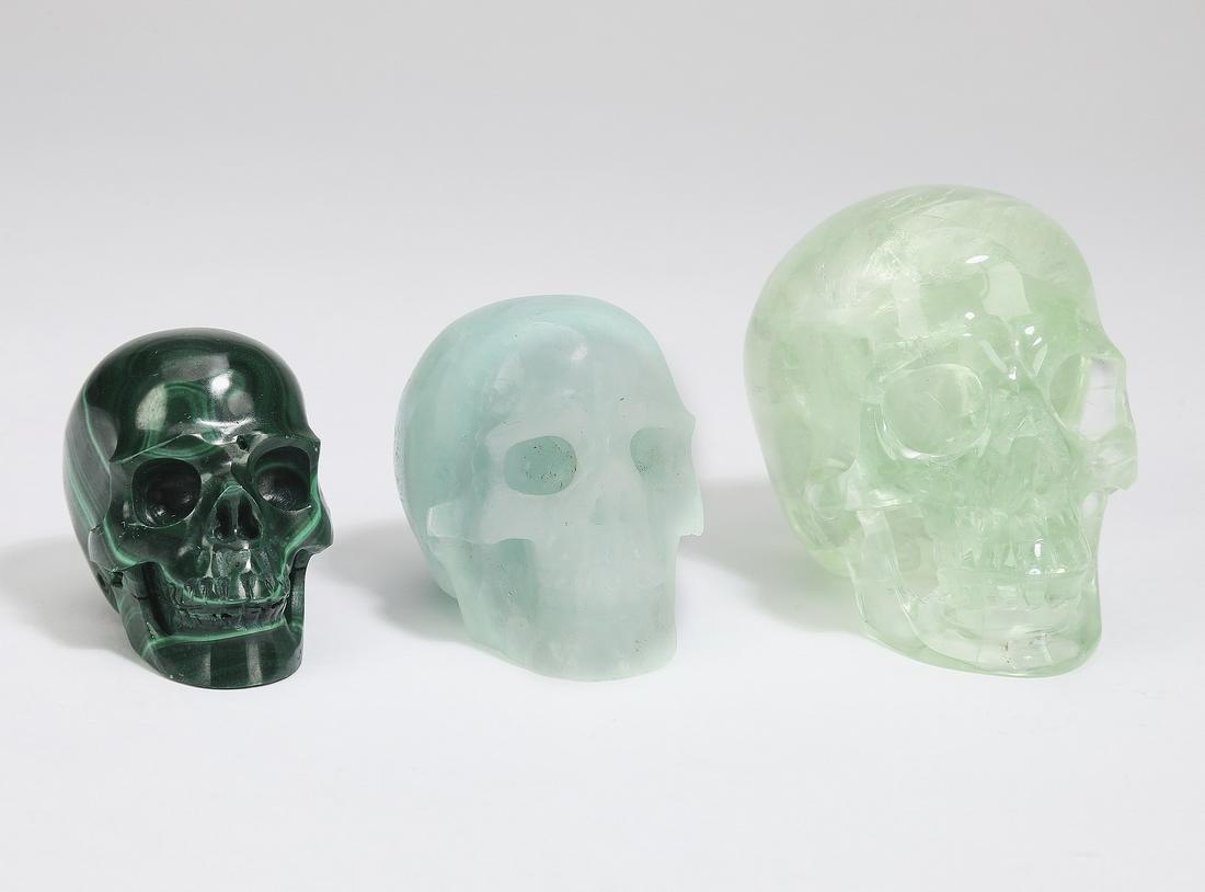 (3) Carved mineral specimen skulls: Three carved mineral specimen skulls, comprising a malachite, a green aventurine, and a green florite, largest 2.25"h x 2"w x 2.5"d.
