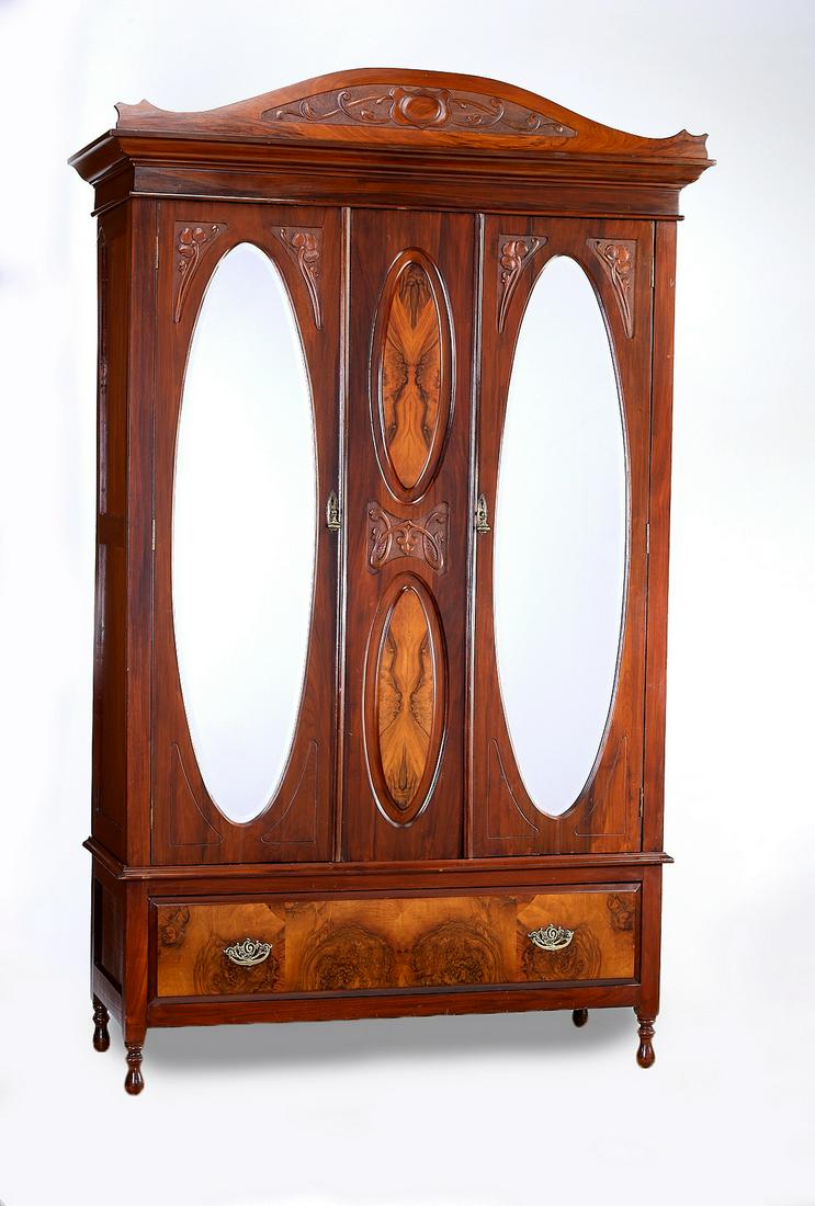 Art Nouveau mahogany mirrored armoire: Art Nouveau mahogany armoire, late 19th or early 20th century, having a relief carved arched cornice rising on two doors with inset beveled glass mirrors, centering book matched veneer medallions and 