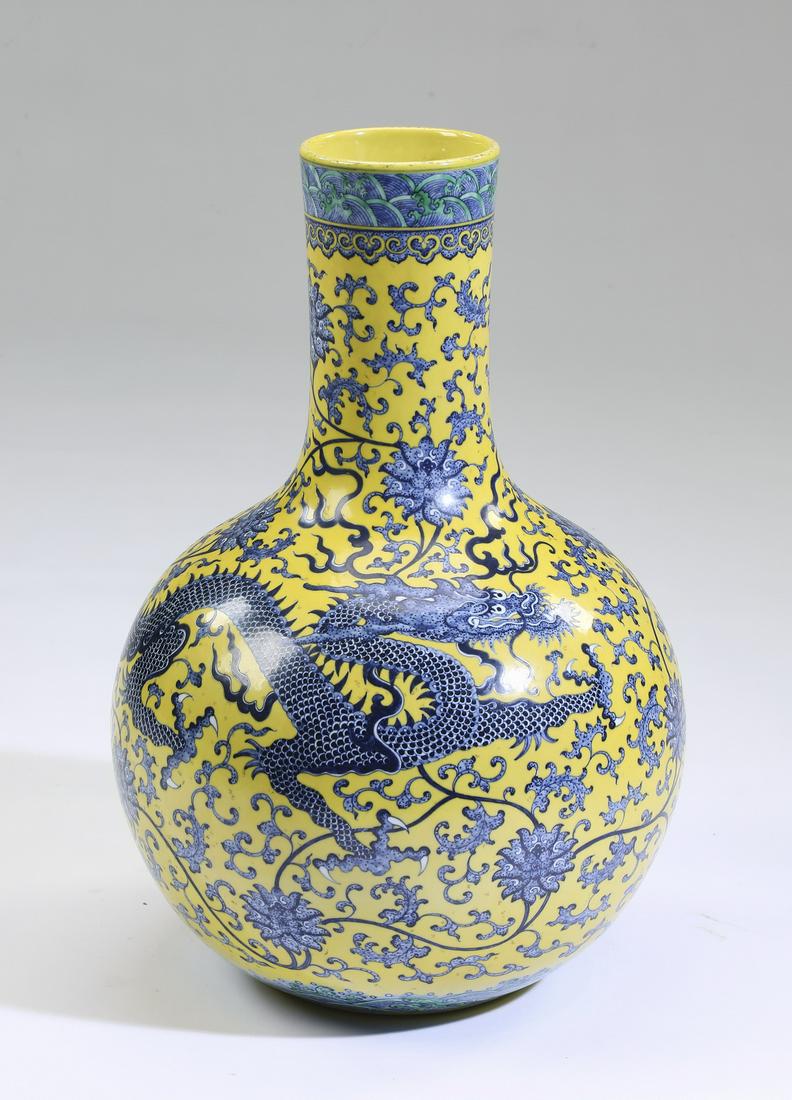Chinese dragon motif and scrollwork vase: Chinese blue, green, and yellow dragon vase, of bottle form, having crashing wave and ruyi bands at the rim, above a cylinder neck and globular body decorated with a writhing dragon amidst lotus scrol