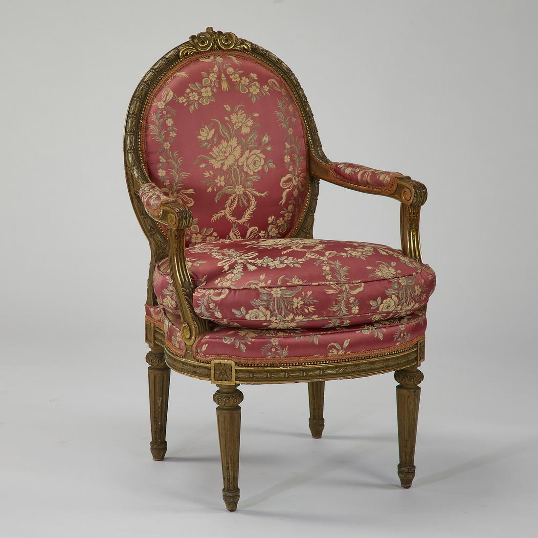 19th c. silk upholstered French fauteuil: Louis XVI style paint decorated fauteuil, late 19th or early 20th century, having a balloon back with a floral crest and a carved laurel frame, flowing into partially upholstered arms, above a drop-in