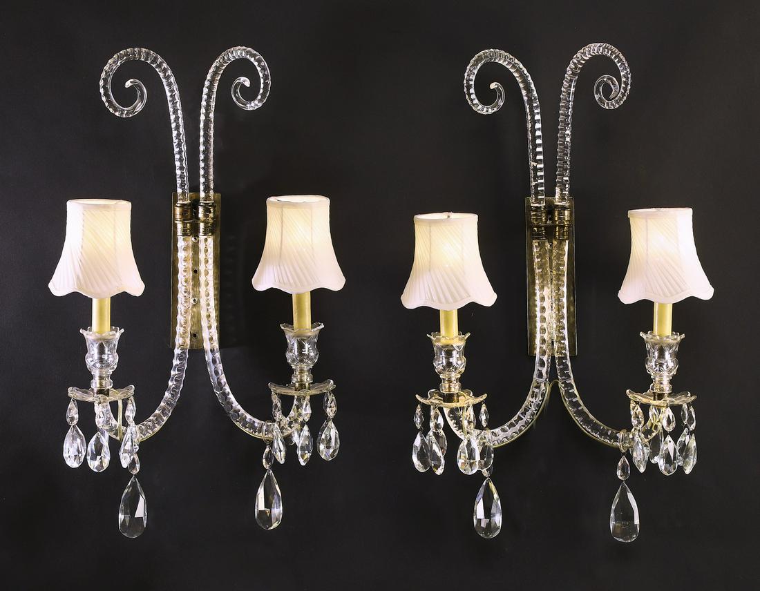 (2) Louis XV style 2- light crystal sconce: Pair of Continental two light crystal sconces in the Louis XV taste, each having two faceted C-scrolling arms terminating to candle cups hung with tear drop crystals, and having cream diagonally pleat