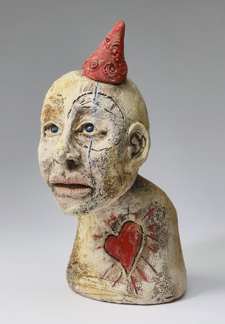 Signed American folk art plaster clown bust, 10"h: Signed American folk art clown bust, 20th century, executed in paint-decorated plaster, depicting a bald clown-like man wearing a red pointed hat, his blue glass eyes glancing upwards, with a radiatin