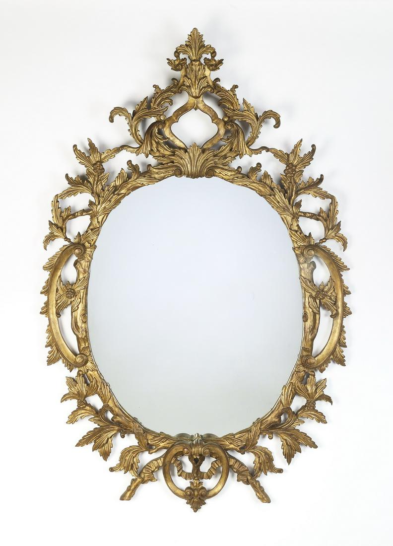 Early 20th c. Rococo style giltwood and gesso mirror: Rococo style giltwood and gesso mirror, early 20th century, having a pierced frame of vines and C-scrolls centering the rounded glass, 58"h x 36"w x 3.5"d.