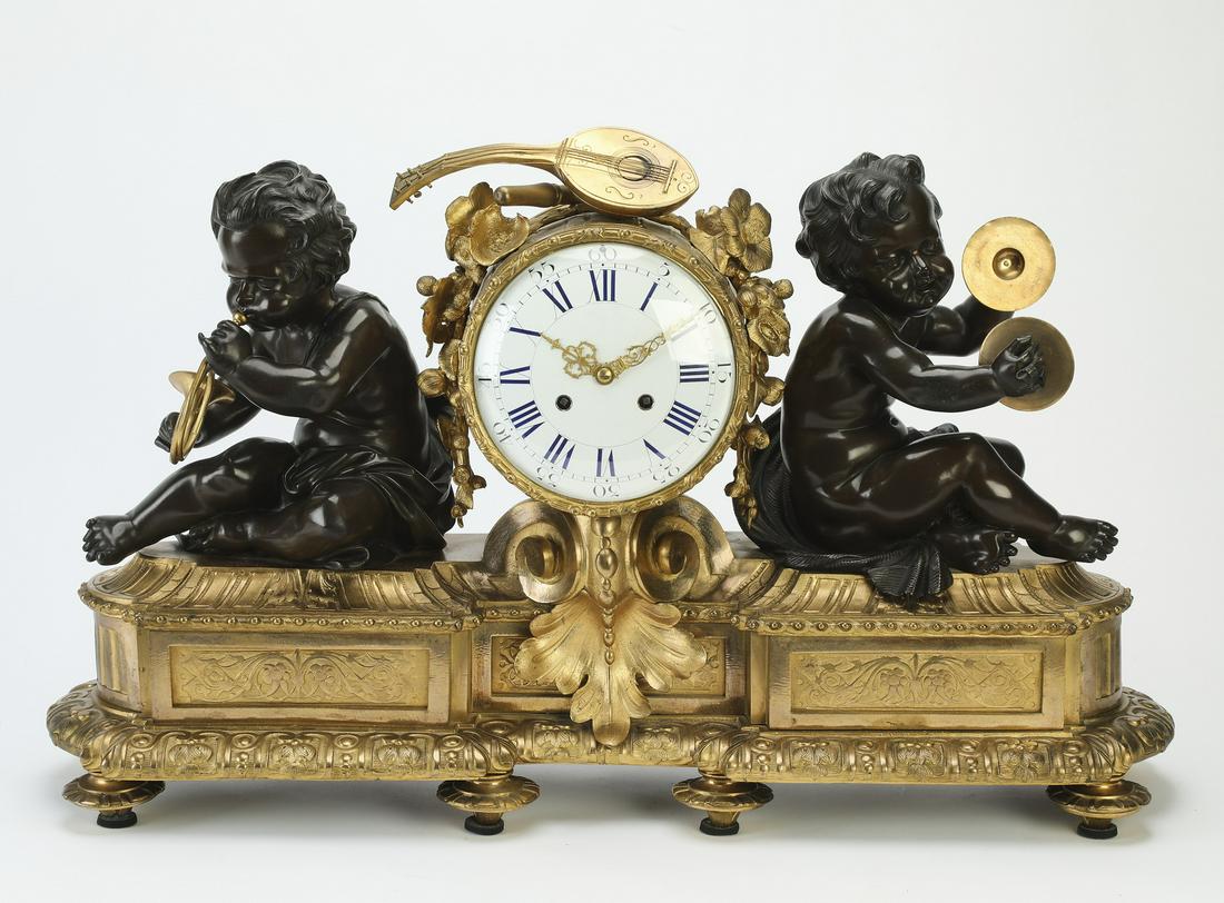19th c. French bronze mantel clock with musical putti: 19th century French figural bronze mantel clock, the porcelain dial paint-decorated with Roman numerals, flanked by musical putti, one playing a horn and the other playing cymbals, rising on an oblong