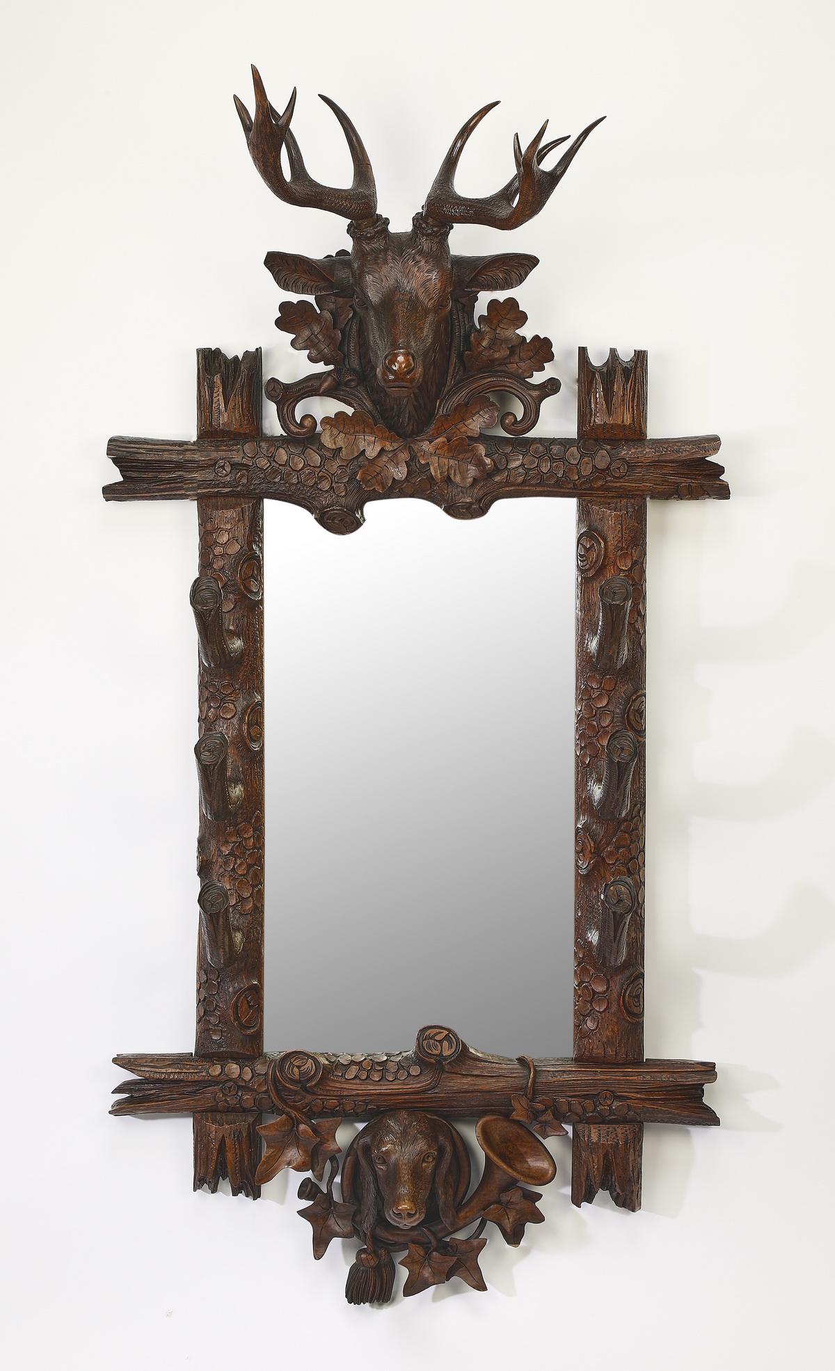 Late 19th c. Black Forest hunting themed wall mirror: Black Forest hunting themed carved walnut mirror, late 19th century, centering a carved buck's head over a mirror surrounded by rustic limbs, naturalistic hooks, oak leaves and acorns, terminating to 