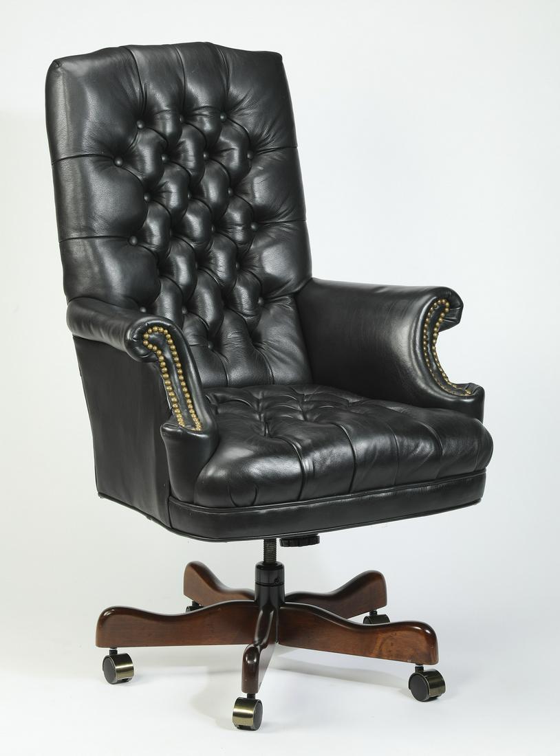 Executive black tufted leather desk chair: Executive black leather desk chair, having a square tufted back above a conforming seat, flanked by scrolled arms with nail-head trim, the whole rising on a 5-spoke wooden swivel base ending in caster