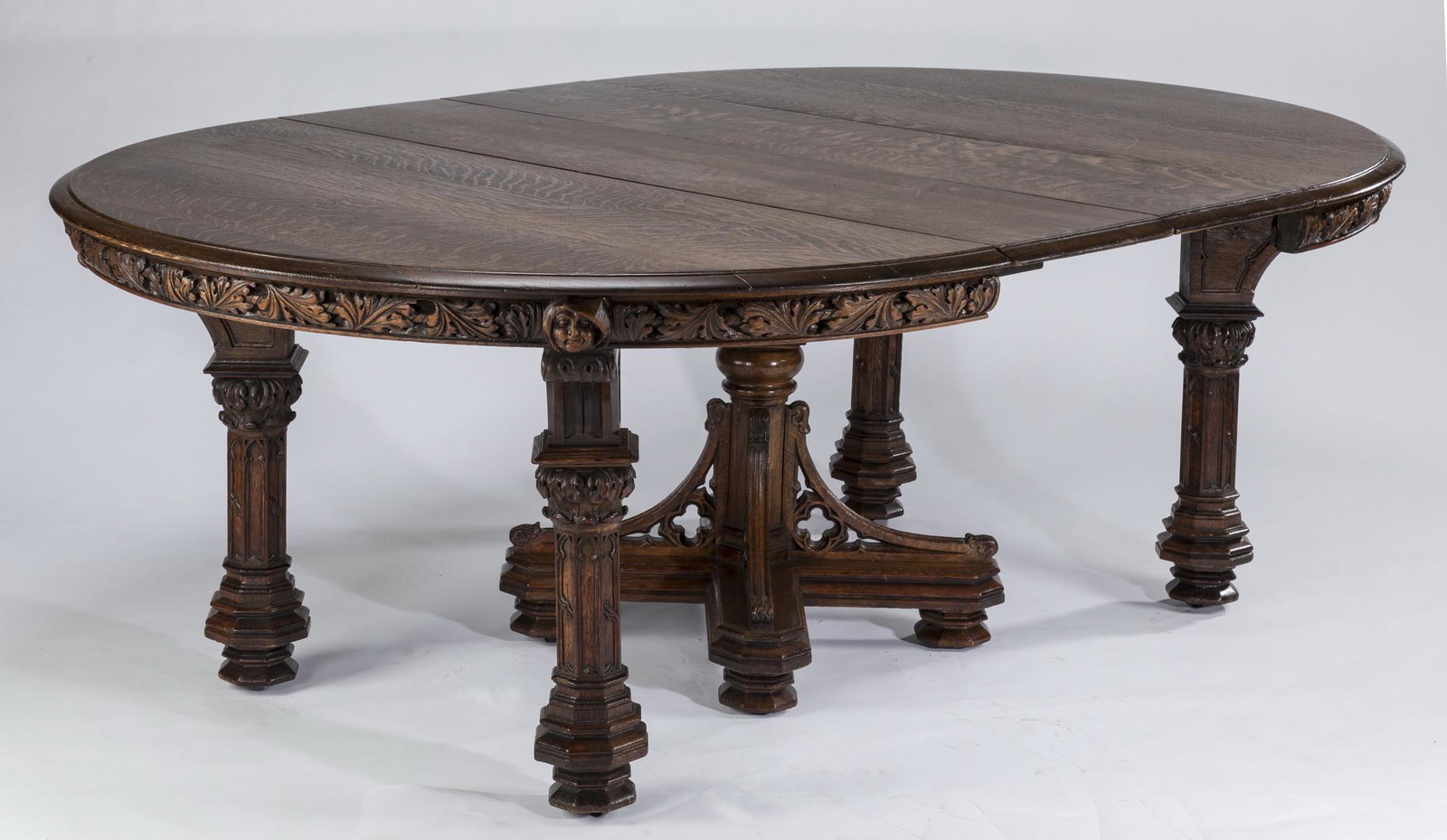 19th c. carved oak Gothic Revival table w/ 2 leaves: 19th century carved quarter sawn golden oak Gothic Revival table with two leaves, the shaped top surmounting the intricately carved apron with acanthus leaves interspaced by relief carved medieval sty