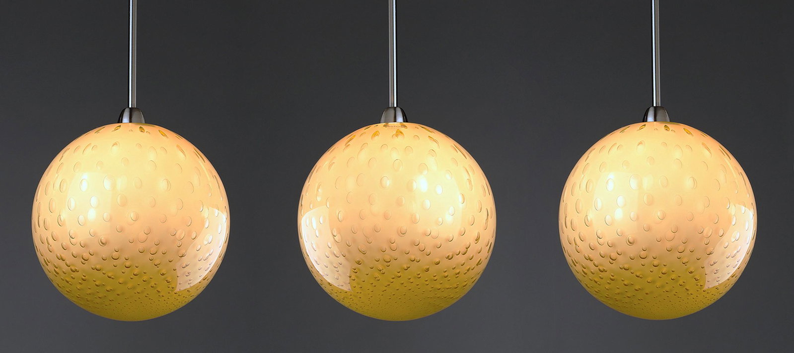 (3) Murano glass 'Bolle' pendants by Vistosi: (3) Contemporary amber Murano glass pendants, designed by Barbara Maggiolo for Vistosi, from the 'Bolle' series, each of spherical form ornamented throughout with small bubbles, and having the appropr