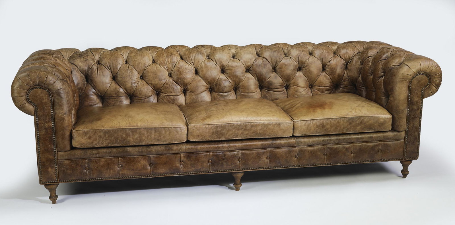 Arhaus leather Chesterfield sofa, 106"l: Arhaus leather Chesterfield sofa, having all over button-tufted detail and a continuous arm centering drop-in seat cushions, the whole rising on turned feet, maker marked to seat, 33"h x 106"l x 39"d,