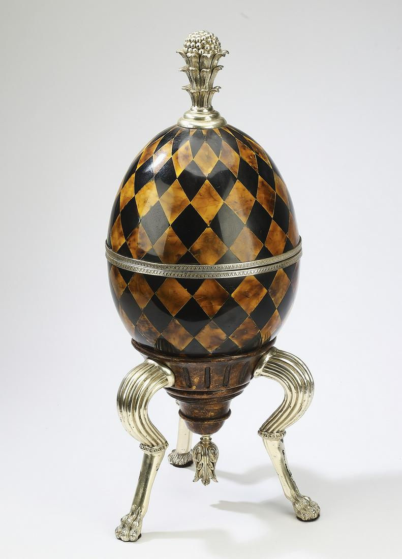 Harlequin egg box on stand: Harlequin egg box on stand, crafted of cast composite and spelter, having a naturalistic finial rising on the egg-form box, decorated in alternating diamonds in black and faux tortoiseshell, the whole