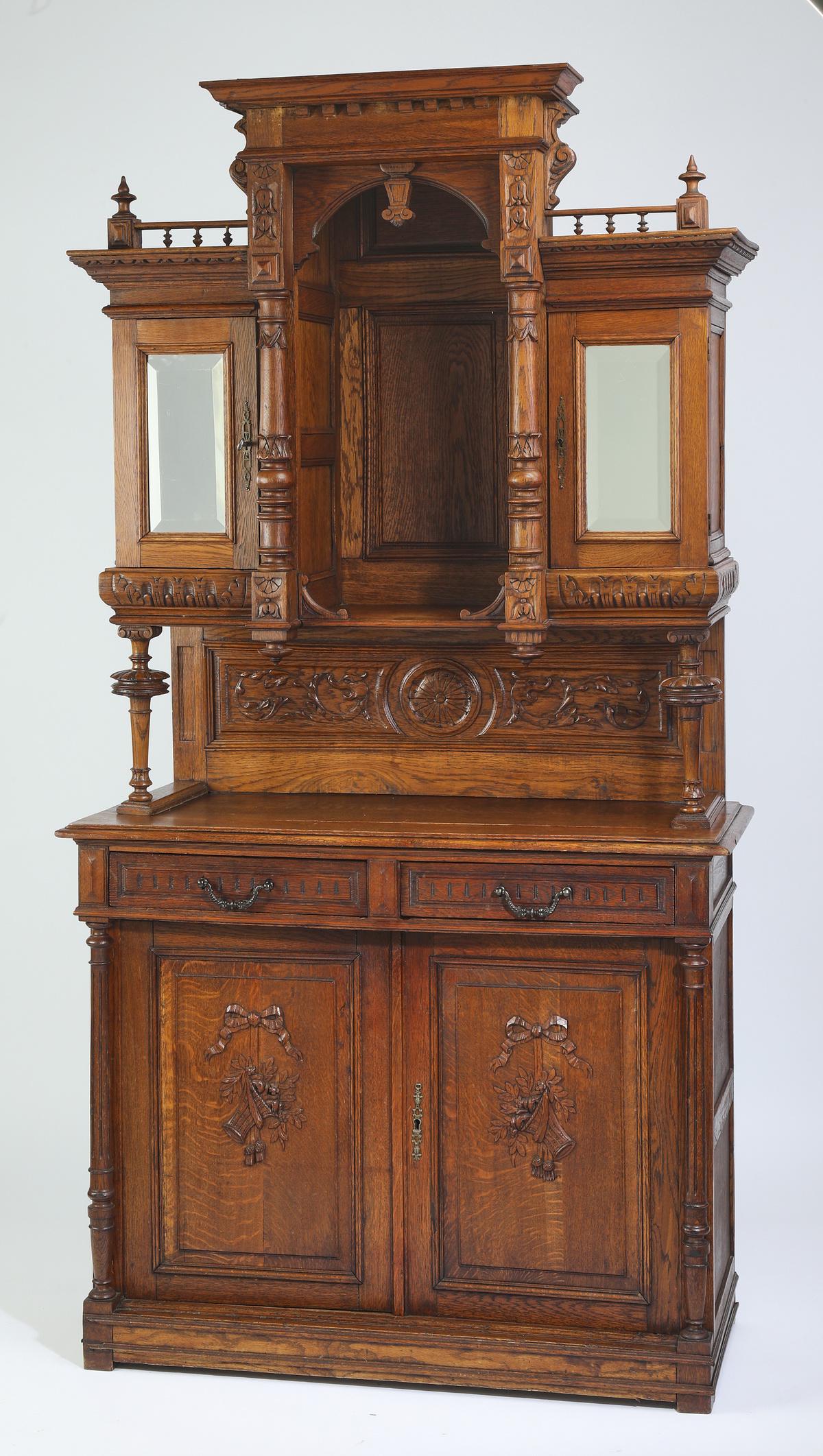 19th c. French carved oak buffet: French Renaissance Revival carved oak buffet, 19th century, having a molded cornice rising on an arched alcove, flanked by mirrored doors, each opening to two shelves, rising on turned standards and a