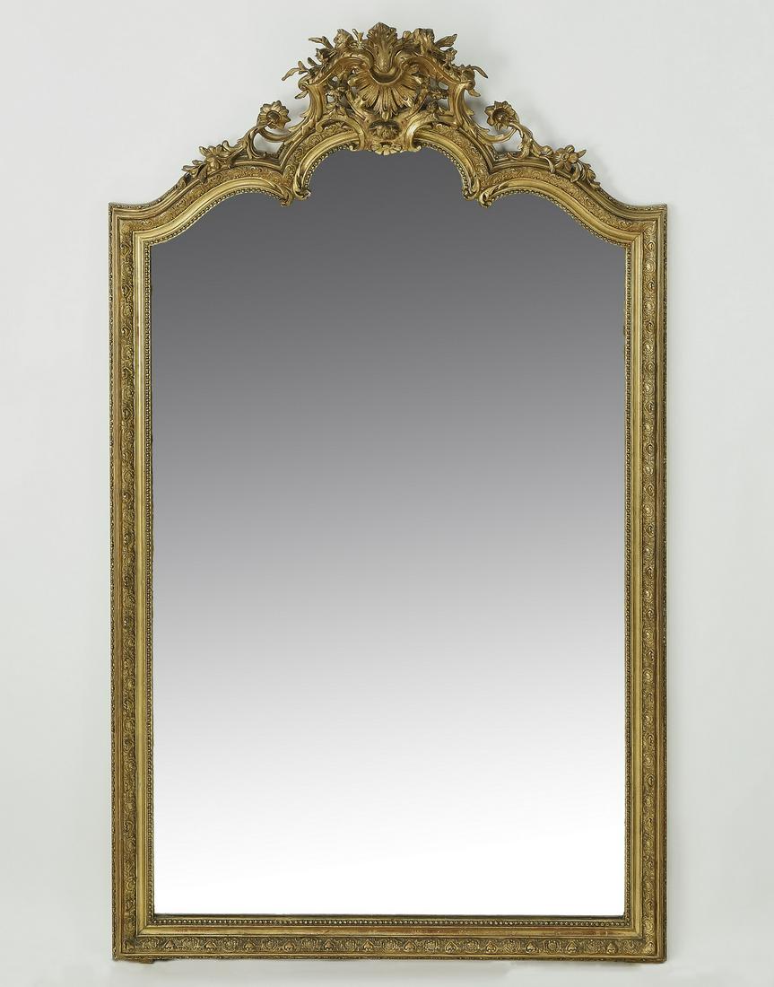 Late 19th c. French Rococo Revival giltwood mirror: Late 19th century French Rococo Revival giltwood mirror, having a pierce carved scallop medallion flanked by rocaille rising on the arched glass, 64"h x 37"w x 7"d.